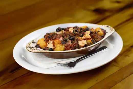 Tater tot bowl topped with seasoned beef, shrimp, cheese, and sliced black olives at Dup’s Pizza & More.
